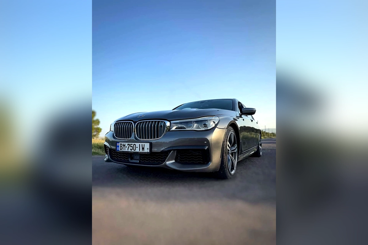 Серый BMW 750 M-пакет на загородной дороге на закате